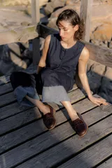 Mocasines negros de cuero con textura tipo cocodrilo en la parte superior y acabado brillante. Presentan una banda frontal clásica y una suela plana con detalle de borde en color natural.