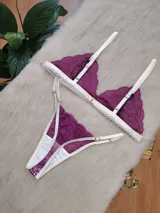 Conjunto de lencería compuesto por un bralette triangular y una tanga, confeccionados en encaje color fucsia con terminaciones y breteles en color crema. El bralette presenta un diseño sin aros con bordes festoneados, mientras que la tanga cuenta con tiras laterales regulables.