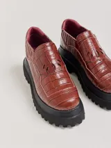 Mocasines color marrón con estampado de cocodrilo y plataforma negra con suela dentada.
