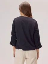 Remera de algodón color blanco, con cuello redondo y mangas tres cuartos con volados escalonados y detalles de pespuntes.