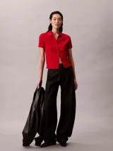 Chomba roja de Calvin Klein confeccionada en algodón con textura jacquard y estampado integral del logo. Cuenta con cuello polo, manga corta, cierre frontal con botones y detalles acanalados en los puños y el dobladillo.