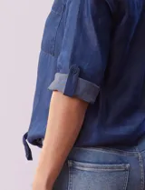 Blusa celeste de tencel, marca Alex & Parker. Cuello a la base, escote en V y abertura central con botones. Delantera con bolsillos. Largo de manga regulable con presilla y botón. Terminación de ruedo con nudo.