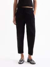 Pantalón tipo babucha de color negro, con cintura elástica y cordón de ajuste, bolsillos laterales y costuras verticales decorativas en el frente.