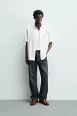 Camisa azul marino de corte regular fit confeccionada en tejido fluido de algodón y lino, con cuello solapa, manga corta, bolsillo aplicado en el pecho y cierre frontal con botones.