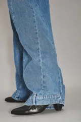 Jean de corte wide leg en color azul medio, con costuras verticales decorativas a lo largo de las piernas y diseño de tiro medio.