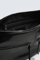 Bolso de hombro de diseño curvo en forma de media luna, confeccionado en material sintético negro. Presenta dos bolsillos frontales con cierre de cremallera y un compartimento principal con cierre. Incluye un asa de hombro integrada y detalles de costuras visibles.