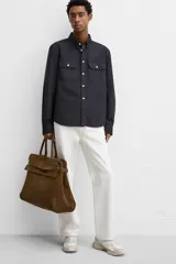 Bolso de mano extragrande color marrón oscuro, estilo tote o satchel, fabricado en piel. Presenta dos asas de mano y un detalle de cinta ajustable con cierre de solapa en la parte frontal superior.