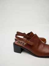 Zuecos clásicos color beige, hechos 100% en cuero vacuno wax y charol, con taco de madera de 5cm de altura y correa trasera ajustable.