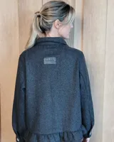 Sobrecamisa de pana color marrón oscuro, con cuello camisero, cierre frontal de botones y detalle de volado en el ruedo. Presenta mangas largas con puños y bolsillos frontales aplicados.