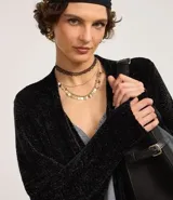 Cardigan largo de chenille con textura acanalada, manga larga y bolsillos delanteros. Presenta un diseño abierto y versátil, ideal para diversas ocasiones.