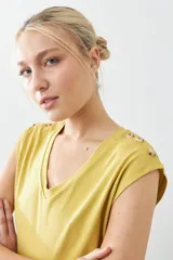 Remera color pistacho con cuello en V y botones decorativos en los hombros.