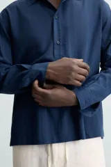Camisa polo de manga larga con cierre frontal de botones, confeccionada en tejido con textura de rayas verticales sutiles.