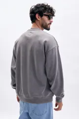 Buzo deportivo gris oscuro con efecto lavado, cuello redondo y corte holgado.