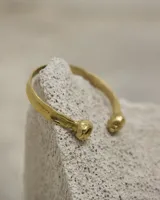 Pulsera esclava abierta de diseño orgánico con terminaciones redondeadas, realizada en metal con acabado texturizado.
