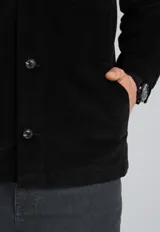 Sobrecamisa negra de pana con cuello clásico, cierre frontal con botones, dos bolsillos de parche con solapa en el pecho y puños abotonados.