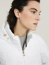 Campera blanca acolchada con cierre de cremallera, cuello alto con capucha, mangas largas y bolsillos laterales con cremallera.