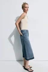 Bermuda larga de jean color azul, tiro medio, con diseño wide leg y bolsillos. Cuenta con bajo desflecado y cierre frontal con cremallera y botón metálico.