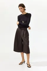 Pantalón palazzo marrón de tiro alto con cierre y corchete oculto, corte holgado con bolsillos en las costuras laterales, bolsillos traseros insertados y piernas amplias con pliegues en la parte delantera.