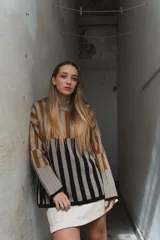 Sweater tejido a rayas horizontales color beige, marrón y negro, de cuello alto y corte holgado.