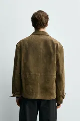 Sobrecamisa relaxed fit de piel con acabado en ante de color verde militar, con cuello solapa, manga larga con puño abotonado, bolsillos de vivo en la cadera y cierre frontal con botones.