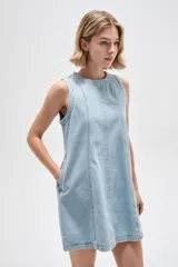Vestido corto de jean blanco con tirantes anchos, cuello redondo, corte holgado y bolsillos laterales.