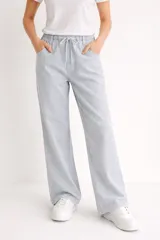 Pantalón de algodón de tiro medio, color celeste claro con finas rayas verticales blancas. Presenta un calce holgado y pierna ancha, con cintura elástica ajustable mediante cordón blanco.