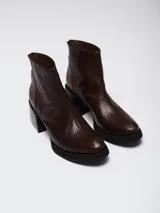 Botinetas de cuero vacuno con textura tipo reptil en color marrón chocolate. Presentan un diseño de caña media con cierre posterior, puntera redondeada y suela de goma con taco cuadrado robusto.