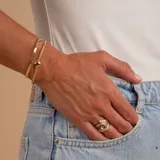 Anillo de oro 10k con diseño de nudo central y bandas laterales decoradas con pequeñas circonias engastadas.