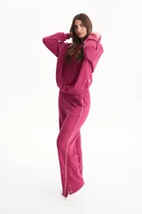 Pantalón deportivo fucsia sin frisa, de corte wide leg, con ribetes blancos en los laterales y aberturas con botones en los tobillos.
