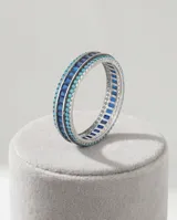 Anillo de plata 925 con diseño de banda, compuesto por una hilera central de circonias cuadradas en color azul zafiro, flanqueadas por dos hileras de pequeñas circonias redondas en color turquesa.