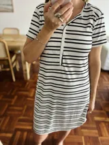 Camisón de manga corta, corte recto, con cuello tipo polo y abertura frontal con botones. Presenta un patrón de rayas horizontales negras sobre fondo blanco.