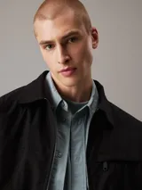 Campera negra de algodón regenerativo con cuello en punta clásico, puños con botones, cierre de cremallera, bolsillos de ojal, bolsillo con cremallera en el pecho, forro completo e insignia con el logo de Calvin Klein en el pecho.