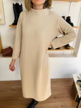 Vestido midi color beige de tejido acanalado, con cuello alto y mangas largas.
