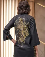 Túnica negra de gabardina de lana con estampado artesanal en tonos ocres. Cuenta con cuello mao, bolsillos laterales y dos piezas a modo de bufandas que se pueden anudar de diferentes maneras.