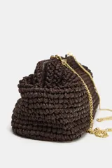 Bolso tipo sobre color marrón, con cuerpo trenzado y asa de mano rígida dorada. Incluye correa bandolera de cadena extraíble y cierre magnético.