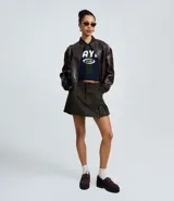 Short pollera de gamuza sintética color verde oliva, con diseño de tablas en el ruedo, cintura con trabillas y bolsillos delanteros.