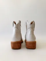 Botas texanas de cuero color gris claro, con caña baja, puntera cuadrada y taco de madera.