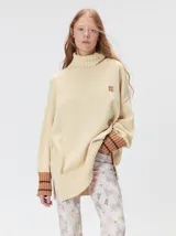 Pullover de cuello tortuga color marrón, de corte holgado y diseño básico. Presenta puños acanalados en contraste de color bordó con líneas horizontales celestes.