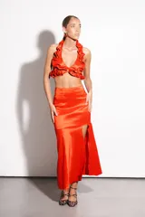 Falda larga roja de tafeta, ajustada en la cintura y con volado amplio con tajo lateral.