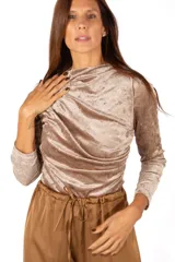 Body de terciopelo color beige, con cuello alto y diseño drapeado en el frente. Posee mangas largas y ajuste al cuerpo.