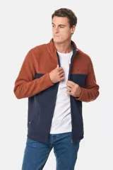 Campera de micro polar bondeado con diseño bicolor, combinando paneles en color terracota y azul marino. Presenta cuello alto, cierre frontal completo y bolsillos laterales con cierre.