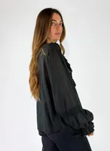 Blusa de algodón blanca con escote en V, mangas largas amplias y detalles de volados con encaje bordado en el frente.