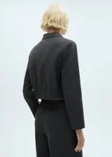 Chaqueta corta de tweed a cuadros grises, con cuello camisero, solapas decorativas, cierre frontal con botones y bajo con goma elástica.