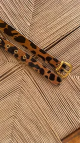 Cinturón de cuero metalizado en tono dorado, con hebilla metálica dorada y ojales reforzados.