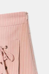 Falda mini de tiro bajo color rosado con estampado de rayas verticales. Presenta dos bolsillos de parche en el frente con detalles de cordones cruzados ajustables y cierre lateral con cremallera oculta.
