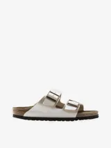 Sandalia Birkenstock modelo Arizona de dos tiras, color blanco nacarado brillante. Presenta hebillas ajustables de metal color cobre y plantilla anatómica de corcho-látex forrada en ante.