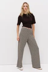 Pantalón de punto suave con patrón de rayas horizontales en color marrón y blanco, tiro medio con cintura elástica, cordón ajustable y piernas amplias de corte recto.