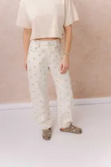 Jean de tiro alto confeccionado en denim color crudo, con estampa de estrellas en tono camel. Presenta calce relajado, pierna recta levemente amplia, costuras verticales delanteras, cinco bolsillos, pasacintos y detalle metálico en la parte posterior.