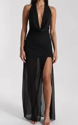 Vestido largo negro con escote halter profundo drapeado y falda larga con transparencias y tajo lateral.