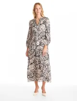 Vestido maxi de satén con estampado floral en tonos negro y beige. Presenta escote en V, hombros fruncidos, mangas largas con puños elásticos y cintura con detalle de punto smock. La falda tiene un diseño escalonado con vuelo.